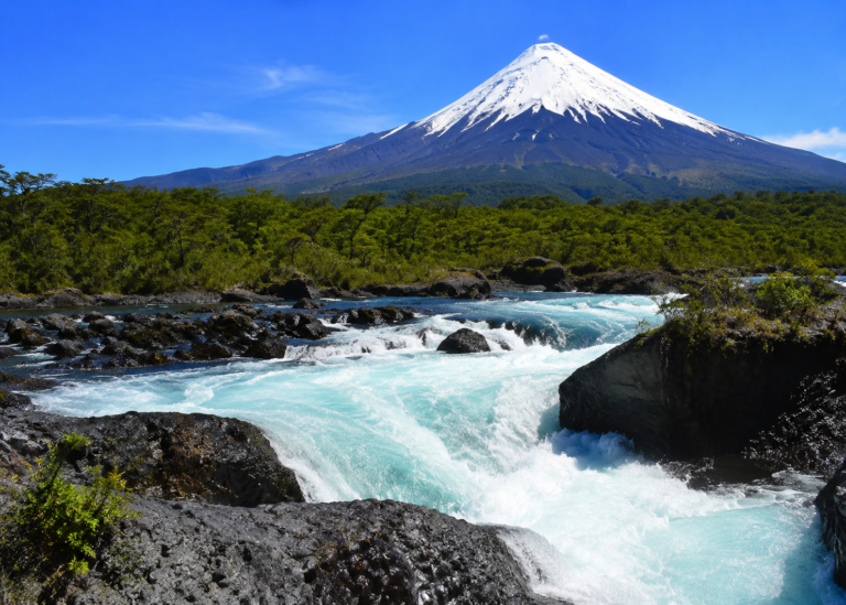 Vista panorámica de los Saltos del Petrohué con aguas turquesa, rocas volcánicas y el volcán Osorno al fondo en la Región de Los Lagos, Chile.